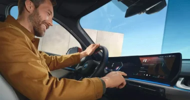 Interior de veículo BMW mostrando smartphone com chave digital próximo ao volante