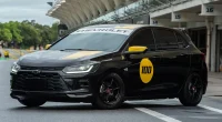 Chevrolet Onix Track Day com faixas amarelas e número 100 na porta em pista de corrida