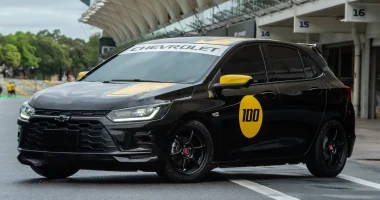 Chevrolet Onix Track Day com faixas amarelas e número 100 na porta em pista de corrida