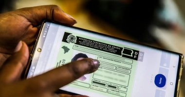 Smartphone exibindo aplicativo da CNH digital com confirmação de renovação dentro de um carro