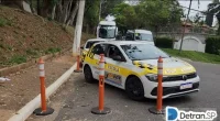 Carro de autoescola realizando manobra de estacionamento próximo ao meio-fio sob supervisão de instrutor.