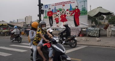 Ruas congestionadas em Ho Chi Minh com motocicletas a gasolina e elétricas, destacando o desafio de infraestrutura em prédios residenciais.