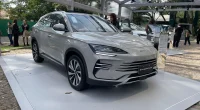 Showroom de concessionária com carros híbridos em exposição e estação de carregamento em destaque