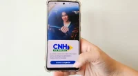 Smartphone exibindo aplicativo da CNH digital com painel de carro desfocado ao fundo