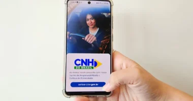 Smartphone exibindo aplicativo da CNH digital com painel de carro desfocado ao fundo