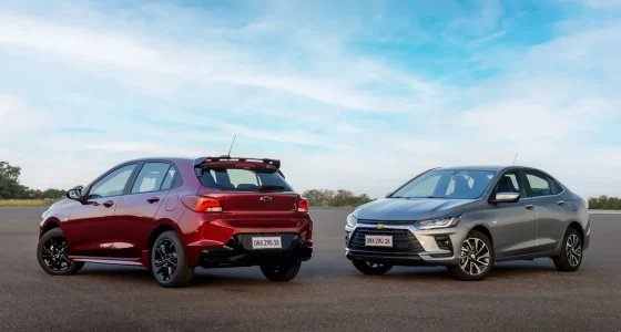 Carro compacto branco transitando em rodovia ensolarada representando eficiência energética