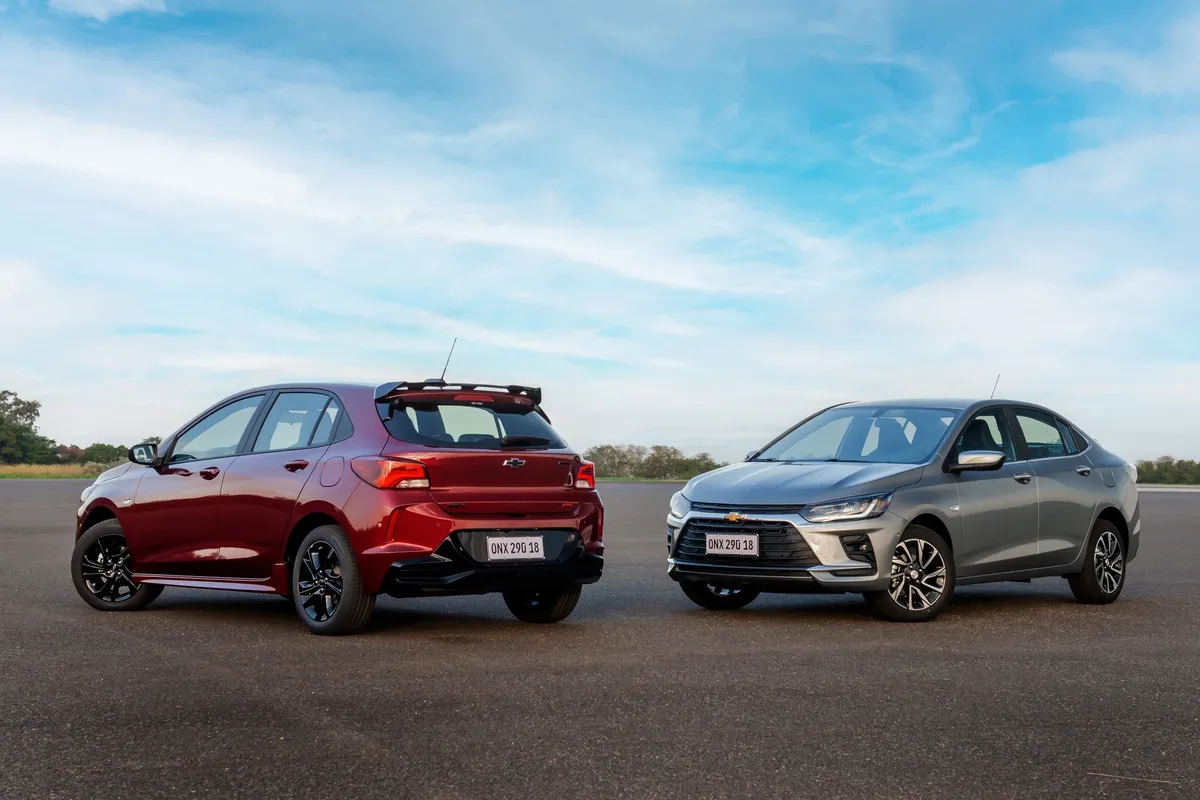 Carro compacto branco transitando em rodovia ensolarada representando eficiência energética