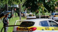Carro de autoescola realizando manobra de estacionamento simples próximo ao meio-fio demarcado por cones.