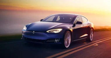 Tesla Model S trafegando em estrada moderna ao pôr do sol